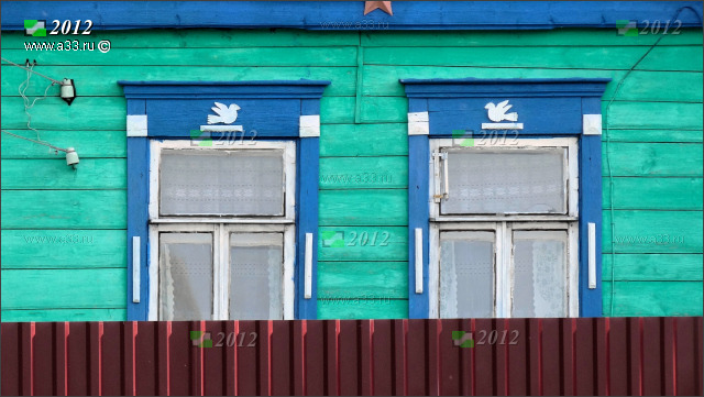 За забором дома в Дубасово Гусь-Хрустального района Владимирской области видны простые деревянные наличники с птичками