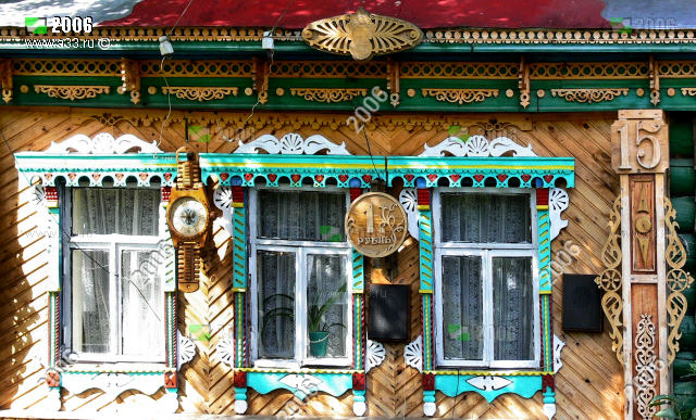 Деревянные наличники окон дома 15 в деревни Курбатиха Вязниковского района Владимирской области дополнены деревянными часами и деревянным рублём